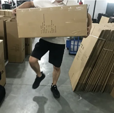 Warehouse quality control worker performing a physical carrying and drop-durability stress test on a heavy export master carton packed with car storage products